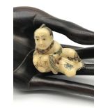 A Japanese hand carved netsuke figure of a musician playing a drum. Highly detailed and signed to