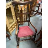 Antique rustic American style spindle back rocking chair. Upholstered with red material and finished