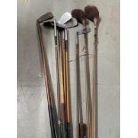 A Vintage golf bag containing vintage golf clubs and two hickory clubs.