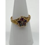 A 19th century ladies gold ring set with various gem stones. Off set by a gold shell to each