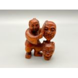 A Japanese hand carved netsuke of a gentleman selling oni masks. Signed by the artist. [4.5cm]