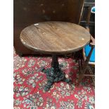 A Heavy cast iron base pub table. Circular wooden top.
