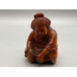 A Japanese hand carved netsuke of an elderly Geisha washing her feet. Signed by the artist.