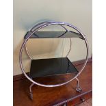 An Art Deco chrome and glass savoy tea trolley. Fitted with black glass shelves and chrome round fr