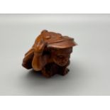 A Hand carved Japanese netsuke of an Oni Monster carrying a large samurai style hat. Signed by the