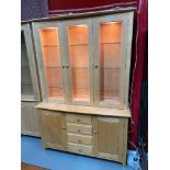 A contemporary light wood ercol display cabinet fitted with glass shelf interior and lighting. [