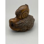 A Hand carved Japanese netsuke of a large toad with a snail sat upon the toads back and two bugs