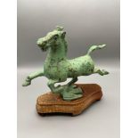 An Oriental Cold painted bronze horse on a flying swallow figure sat upon a hardwood stand.