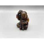 A hand carved Japanese netsuke figurine, depicting a person with a mallet and mouse