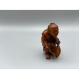 Japanese hand carved netsuke of a gentleman holding a koi carp with black bead eyes, signed by the