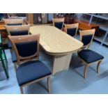 A Contemporary light wood dining table with 6 matching chairs with black upholstery.