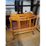 A Reproduction yew wood Canterbury magazine rack with single under drawer and metal caster feet.
