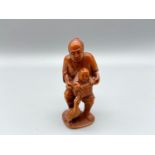 Japanese hand carved netsuke of a gentleman holding a child within a basket, signed by the artist [