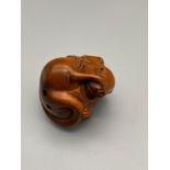 A Japanese hand carved netsuke of a mouse curled up into a ball. Detailed with black bead eyes and