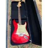 A Red electric guitar with carry case.