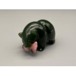A Chinese green jade carved bear holding a pink fish within its mouth. [4cm length]