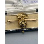 A 16ct gold and enamel Royal Fusiliers bar brooch. [5.91grams]