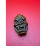 A Japanese hand carved netsuke of an Okimono monster mask, Designed with black bead eyes and