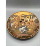 A 20th century Japanese Satsuma hand painted plate depicting various figures, dragon and temple.