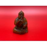 A Japanese hand carved netsuke of a a gentleman smoking a pipe. Signed by the artist.