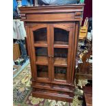 A Contemporary hard wood two door display cabinet. Designed with glass panel doors and sides. Has
