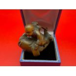 A Japanese hand carved netsuke of a young boy riding a koi carp. Koi carp is designed with black