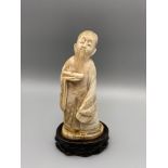 A Meiji period hand carved ivory Scholar figurine displayed with a wooden base. Figure is signed