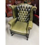 A Green leather Chesterfield button back gull wing chair.
