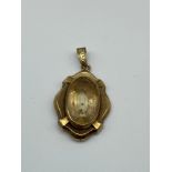 A 9ct gold pendant finished with an oval cut pale yellowish stone. [4.64grams]