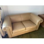 A Contemporary beige leather sofa bed settee with matching button top stool. Only 6 months old.