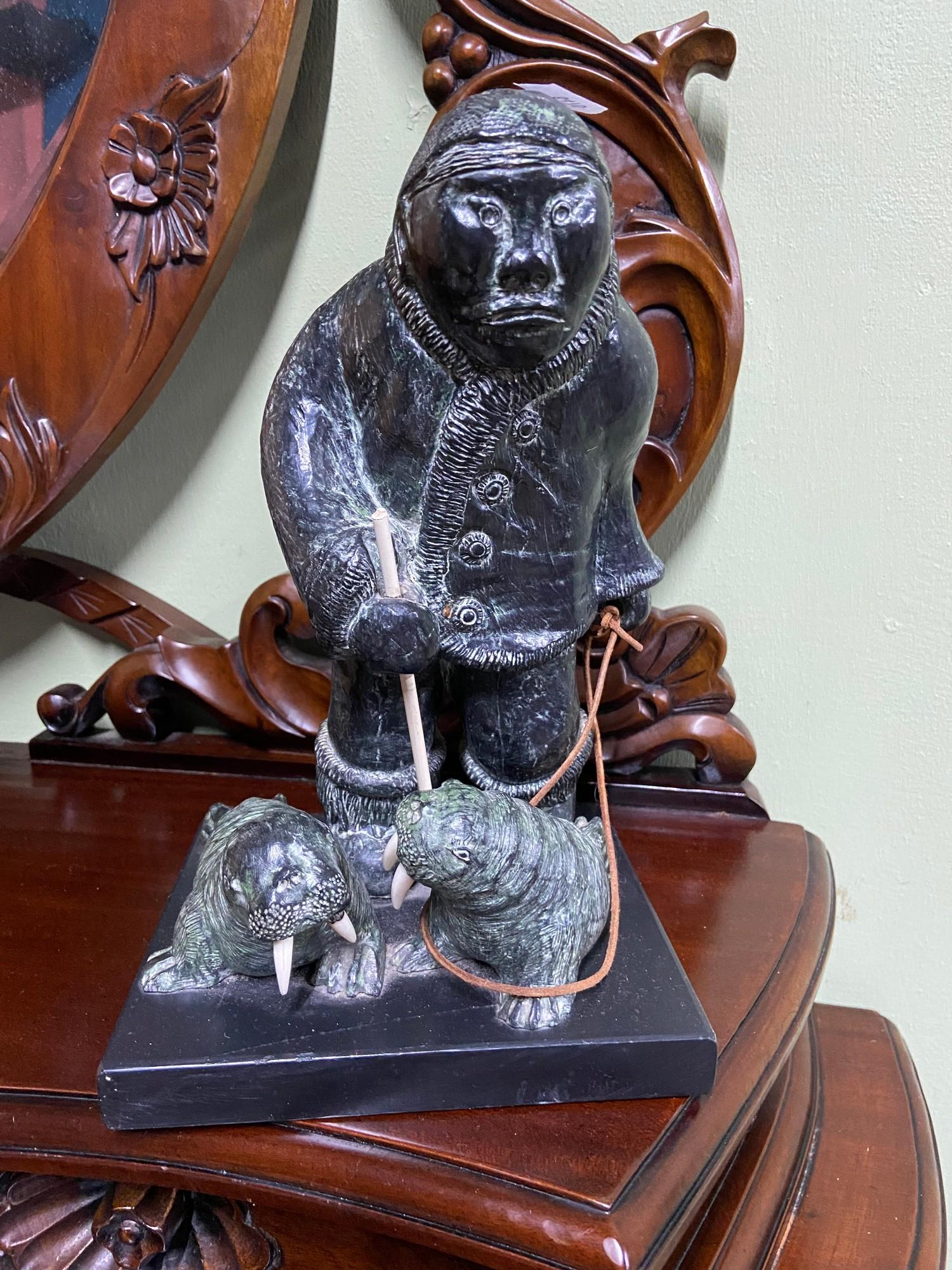 A hand carved stone Eskimo figure and two seals.