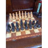 A Vintage wooden folding chess board with hand carved chess pieces.