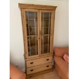 A Victorian stripped pine two door bookcase unit designed with two under drawers. Cabinet is made up