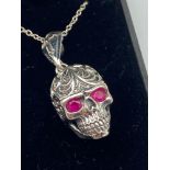 An unusual silver skull pendant and silver chain. The skull has pink hard stone eyes.