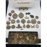 A Tin containing a large quantity of military cap badges and rank bars etc. Includes Scottish Horse,