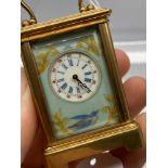 A Brass cased miniature carriage clock designed with porcelain panels. In a working condition. [