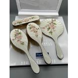 A Four piece London silver and enamel floral design dressing table set. The set consists of a hand
