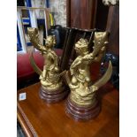 Two gilt painted spelter cherub candle holder. Fitted with wooden turned bases.