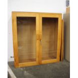 A light walnut finish cabinet enclosed by two glazed panel doors with three adjustable shelves.