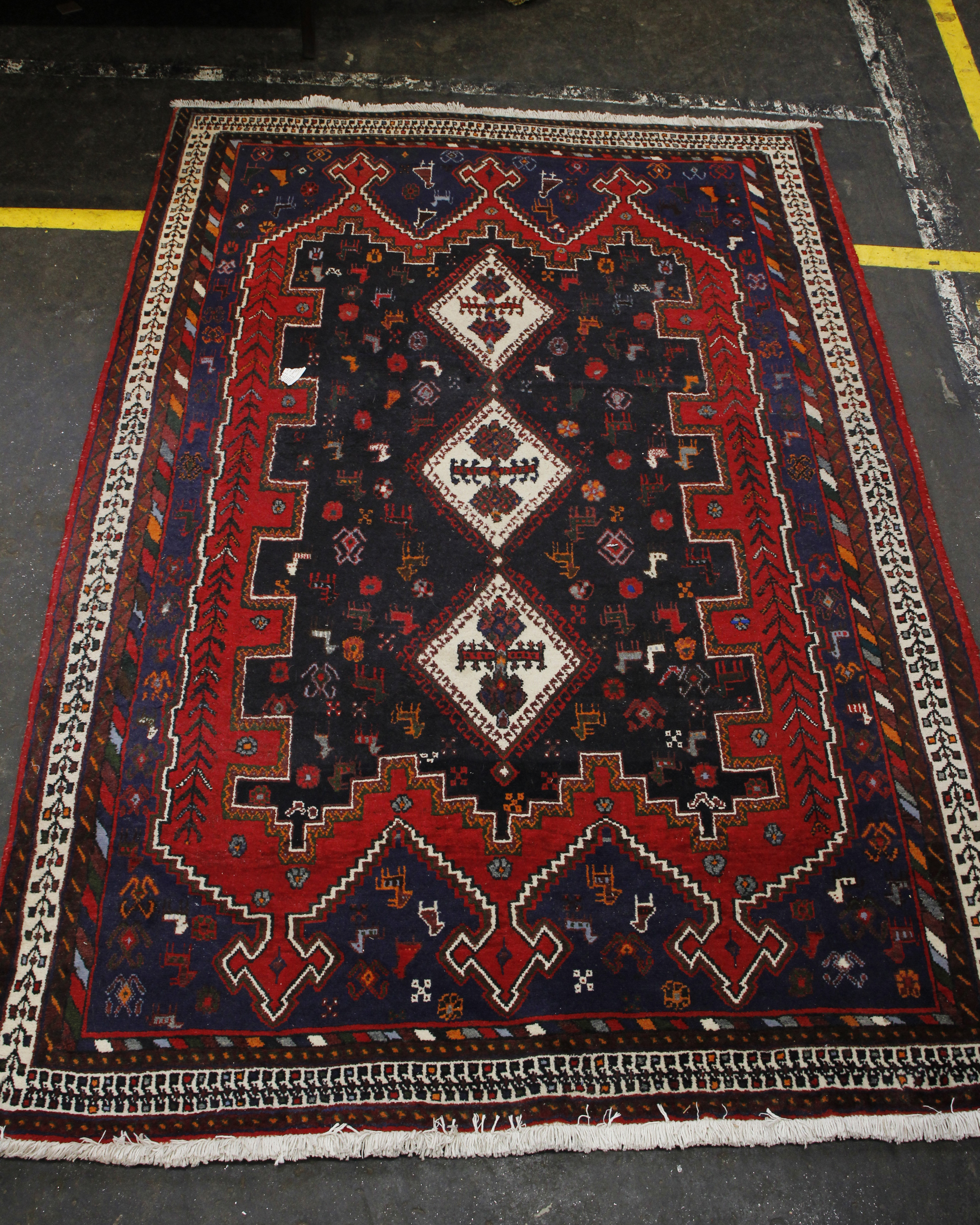 A large Afghan hand knotted wool rug, the geometric patterned central field with cream banded