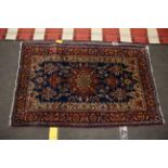 A 20th century hand woven small woollen rug. Red and blue ground with central floral medallion.130cm