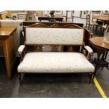 An Edwardian mahogany framed parlour settee upholstered in white and floral fabric in the Sheraton