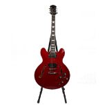 A semi hollow electric six string guitar with a claret red body.