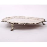 A sterling silver footed card tray raised on three feet with cast foliate border. London 18th