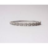 An 18k white gold and diamond set bangle. Half set with marquise and round cut diamonds of uniform