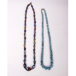 A string of glass and enamel beads together with a string of blue beads.