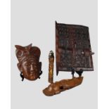 A carved hardwood fertility figure together with two souvenir wall plaques and a North African
