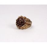 A 9ct gold and red garnet cluster ring with textured shoulders. 6.5g Size M.