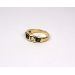 An unmarked yellow metal emerald and diamond ring set with three step cut emeralds and two old