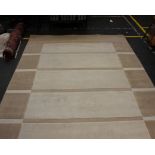 A large cream and fawn coloured rug, 340cm x 240cm